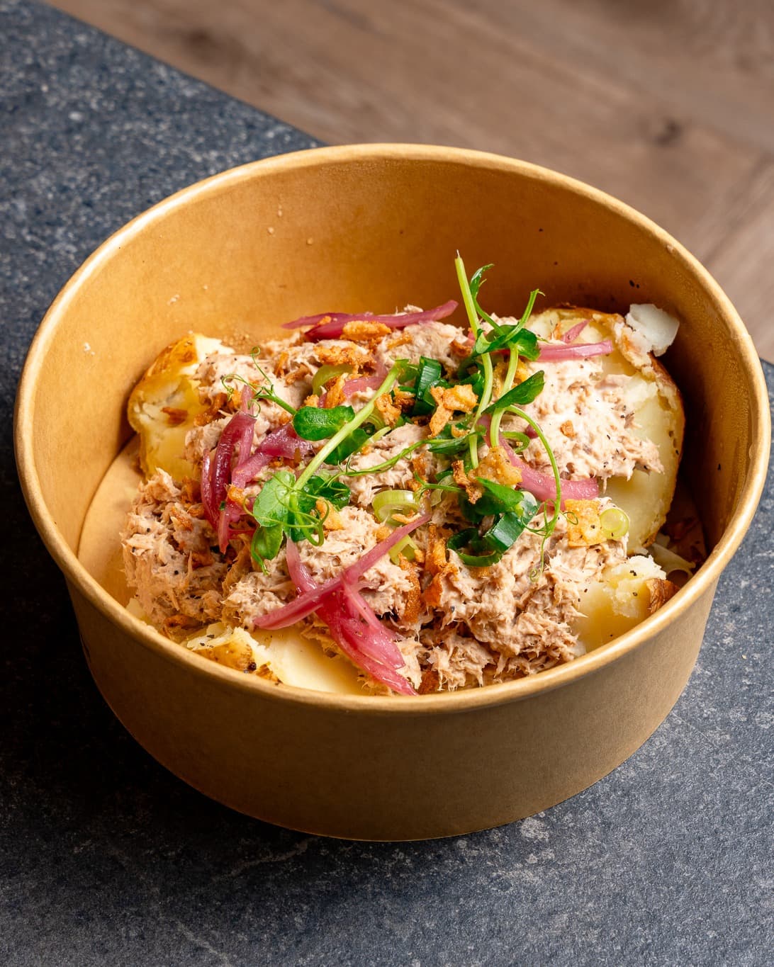 A bowl of potatoes topped with tuna and pickled onions